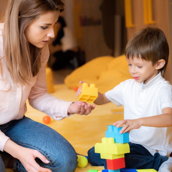 educator-and-adorable-boy-playing-with-constructor-VBAZ943-1.jpg